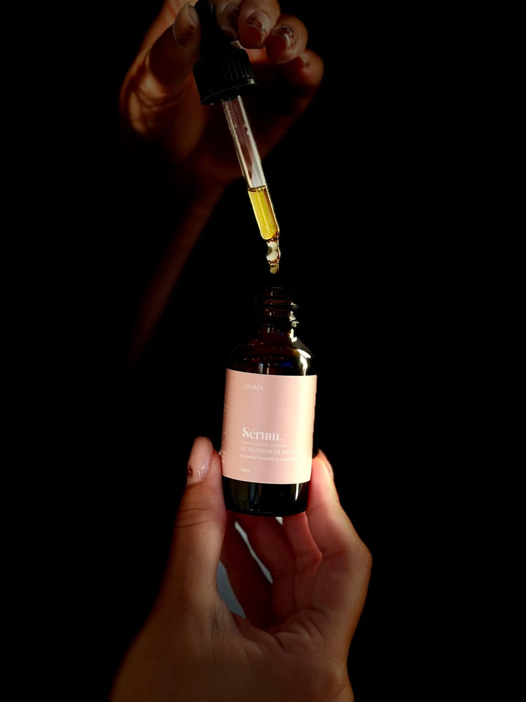 Pipette de sérum au-dessus du flacon, dans la pénombre